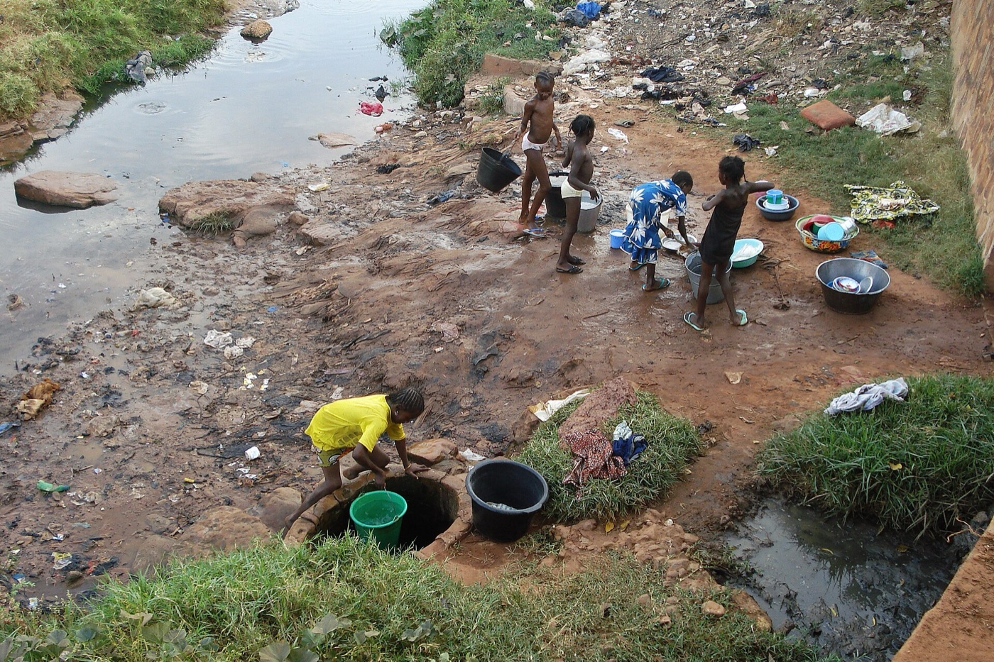 Children washing clothes near a polluted stream in Bobo-Dioulasso